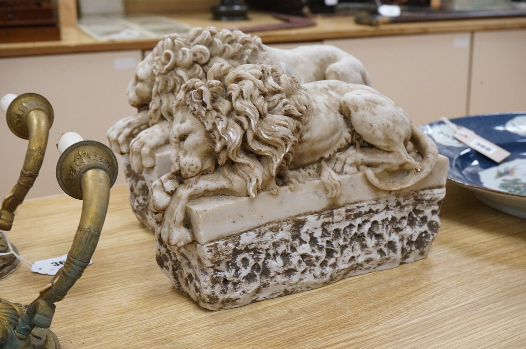 A pair of marble resin Canova lions, 30cm wide